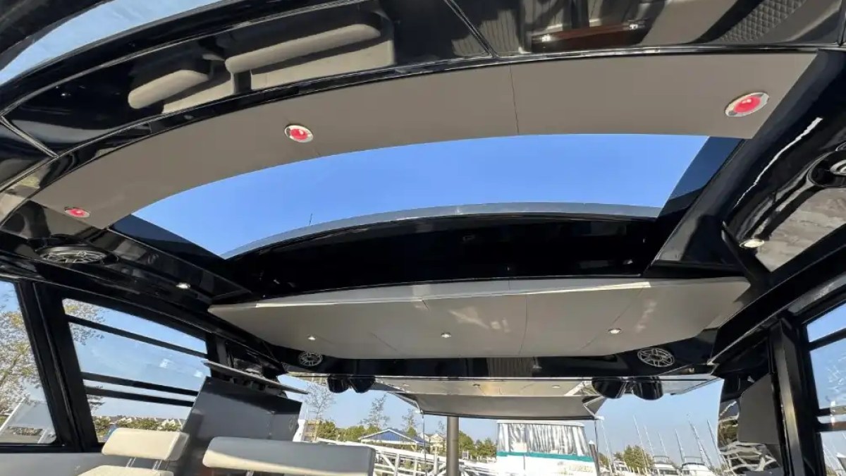 Interior of a boat with an open sunroof and beige seats with a view of the marina.