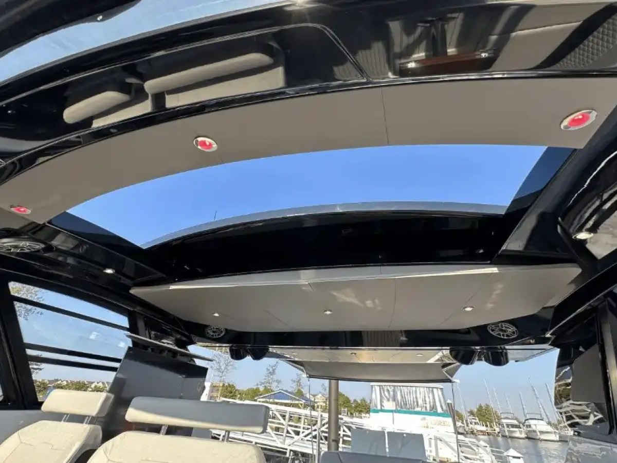 Interior of a boat with an open sunroof and beige seats with a view of the marina.