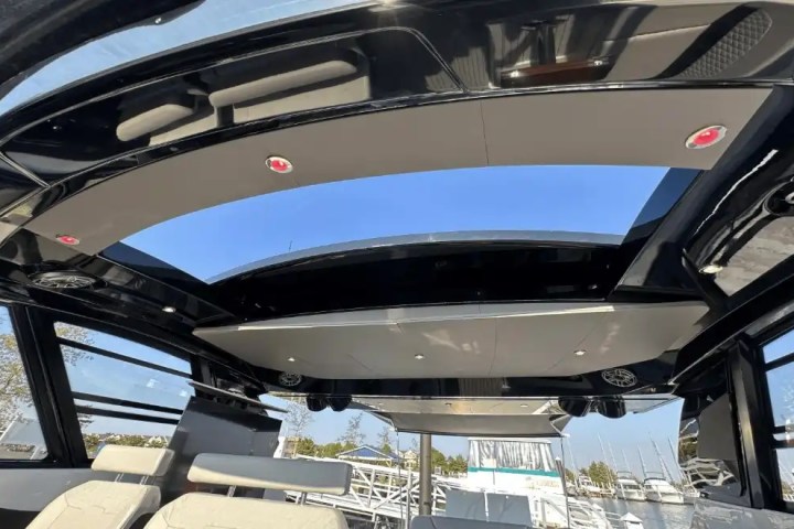 Interior of a boat with an open sunroof and beige seats with a view of the marina.