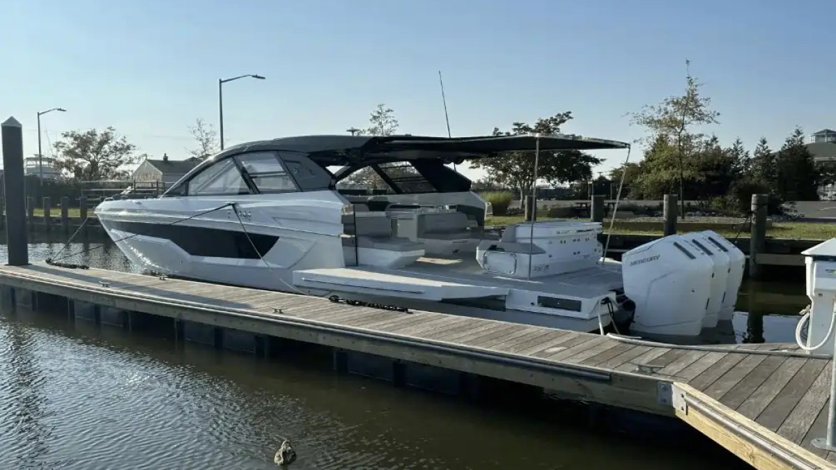 A white motorboat docked in a marina under a clear blue sky.