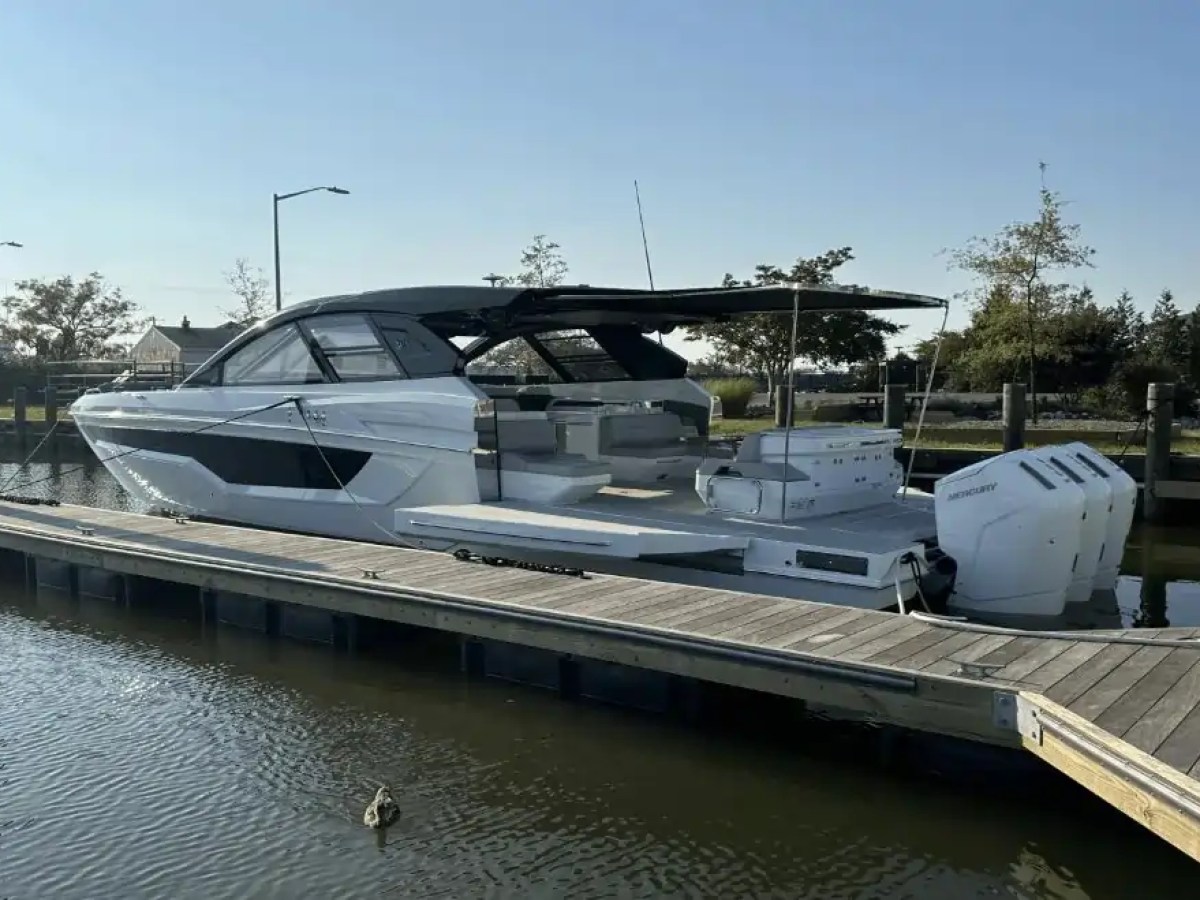 A white motorboat docked in a marina under a clear blue sky.