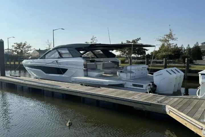 A white motorboat docked in a marina under a clear blue sky.