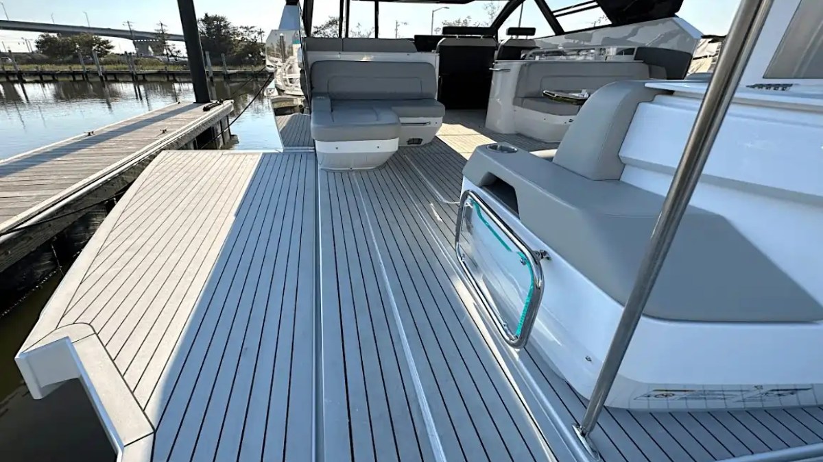 Deck of a modern motorboat with gray seating and railing at a marina.