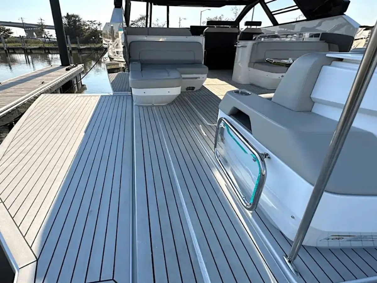 Deck of a modern motorboat with gray seating and railing at a marina.