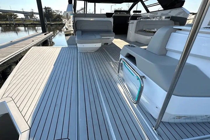 Deck of a modern motorboat with gray seating and railing at a marina.