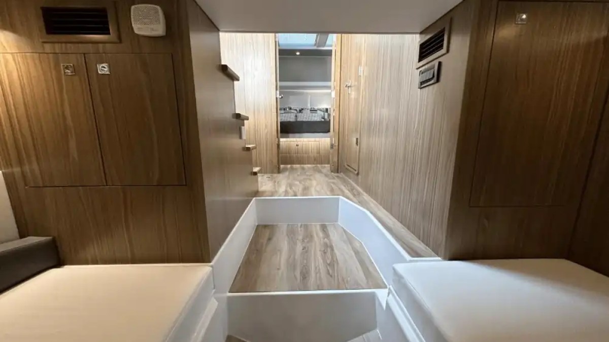 Interior of a minimalist wooden cabin with two white beds and a central walkway.