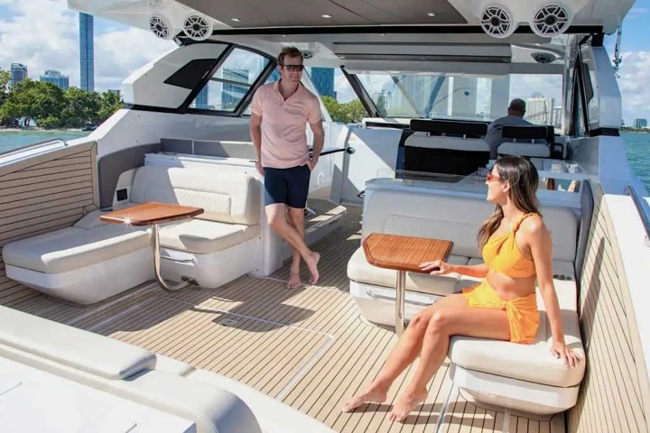 Two people relaxing on a yacht with city skyline in the background.