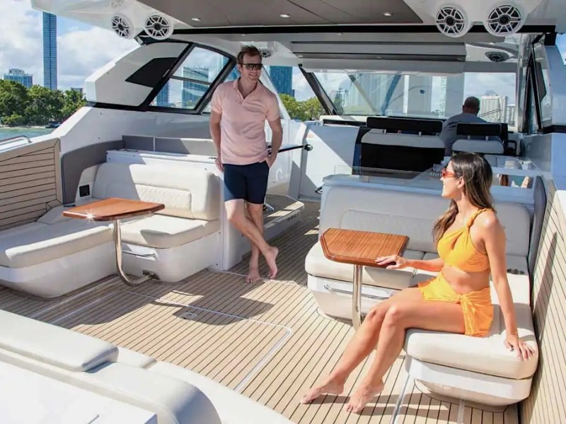 Two people relaxing on a yacht with city skyline in the background.
