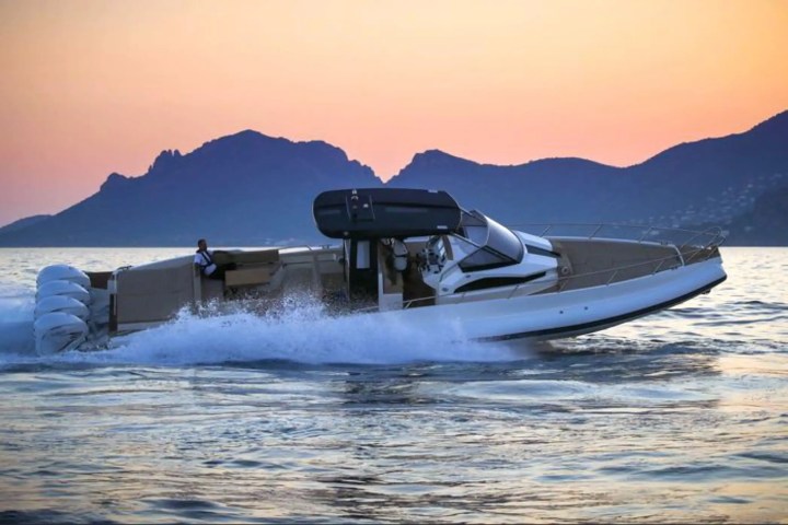 Speedboat on water at sunset with mountains in the background.