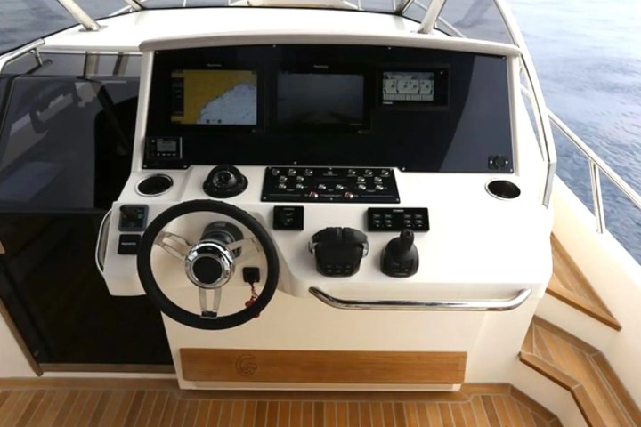 Boat helm with steering wheel, control panels, and navigation screens.