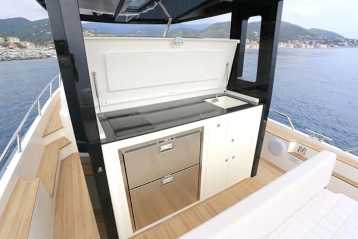 Outdoor yacht kitchenette with sink, stove, and storage drawers view on deck.
