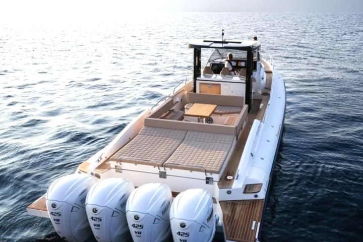 A luxury speedboat with four outboard motors cruising on open water.