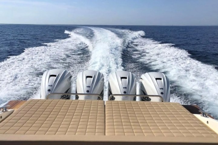 View from boat deck showing four engines and wake in the ocean.
