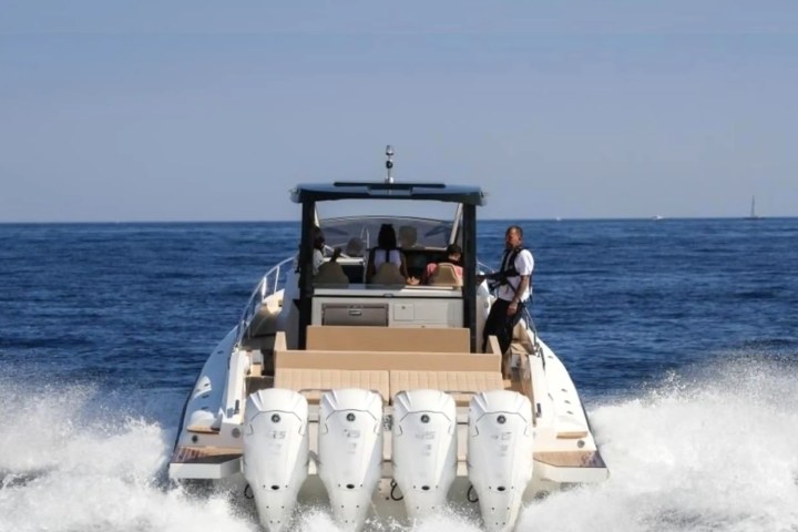Rear view of a motorboat with three engines cruising on open water.