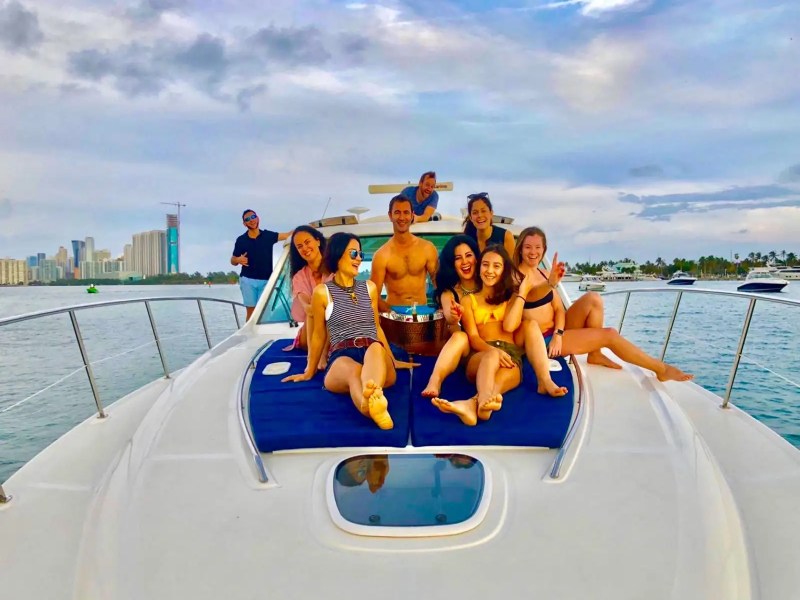 51' SeaRay yacht guests celebrating on the bow with Miami Beach skyline