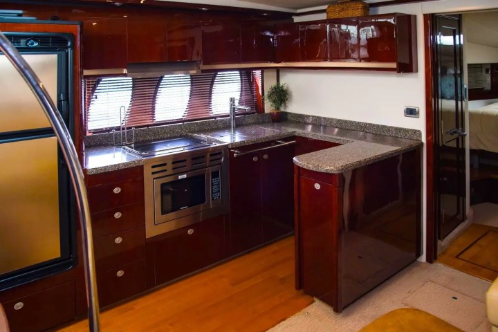 Luxury yacht kitchen with glossy wood cabinets and modern appliances.