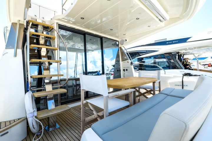 Interior view of a yacht deck with seating, table, and stairs to the upper level.