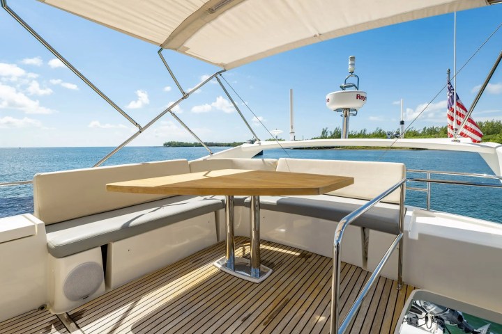 Boat deck with a wooden table, seating, canopy, and ocean view.