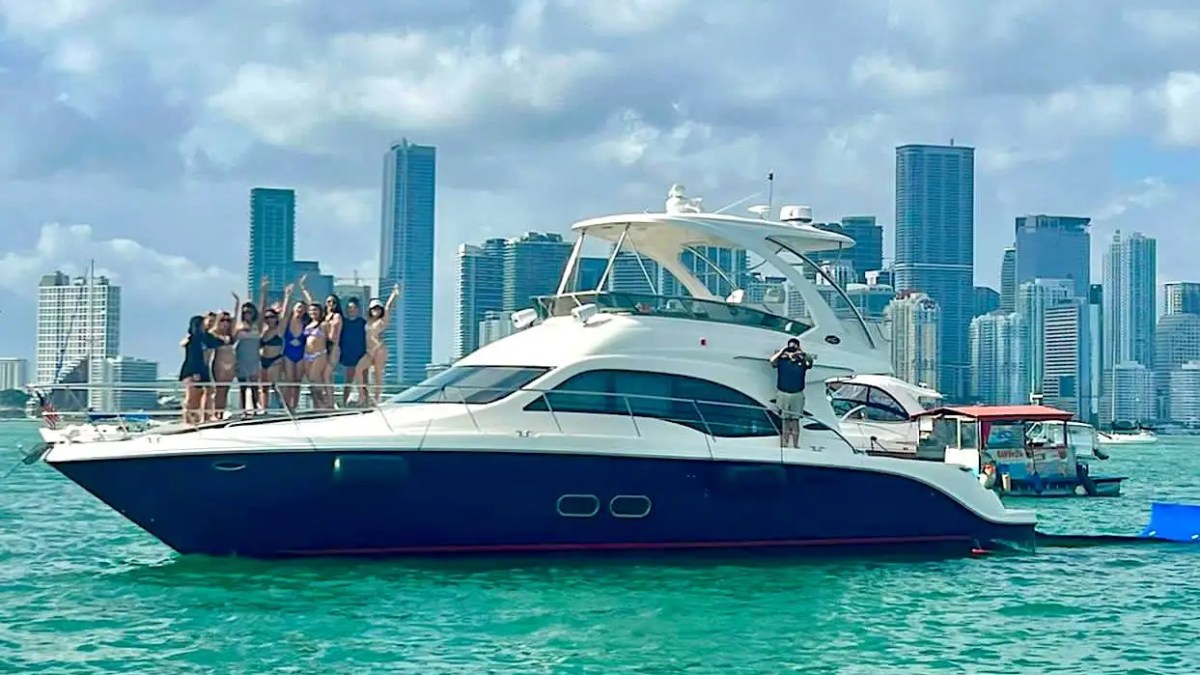 Guests waving from the bow of a 56′ SeaRay yacht in Miami Beach