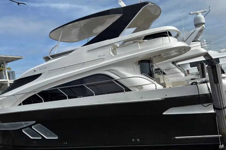 Luxury yacht docked at a marina under a cloudy sky.