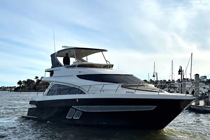 Luxury yacht docked at marina under clear blue sky.