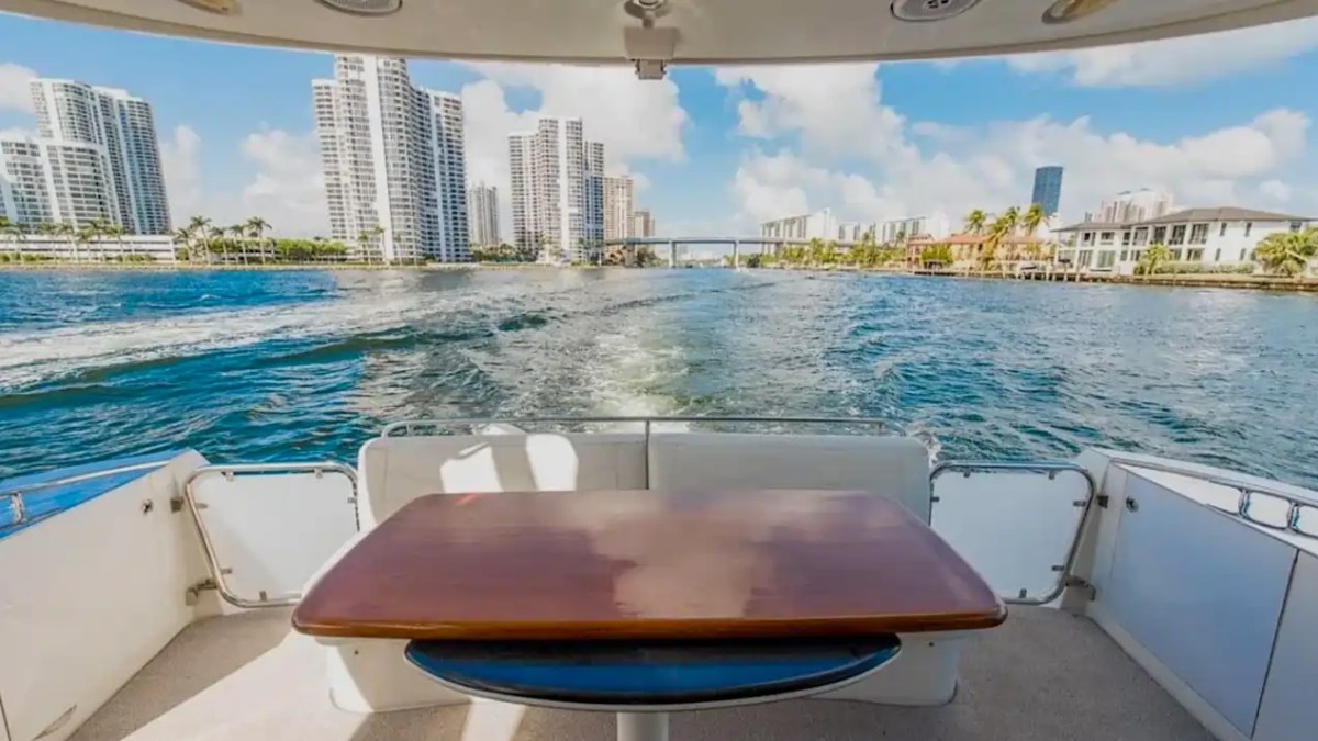 View from boat's deck with table, city skyline and water in background.