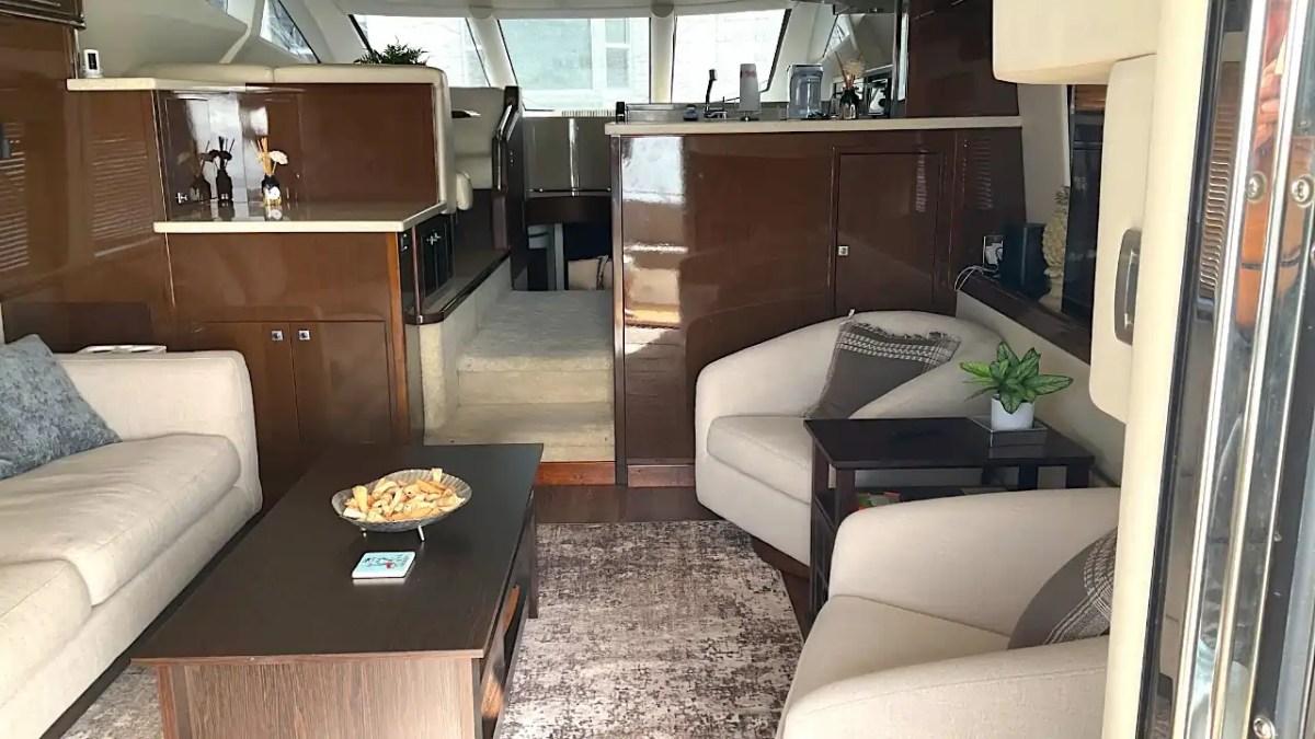 Luxurious yacht interior with sofas, armchairs, and a dark wood coffee table in a modern design.