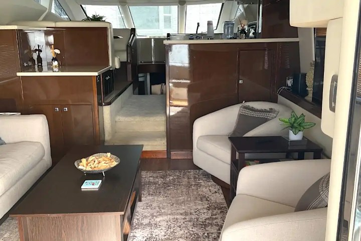 Luxurious yacht interior with sofas, armchairs, and a dark wood coffee table in a modern design.