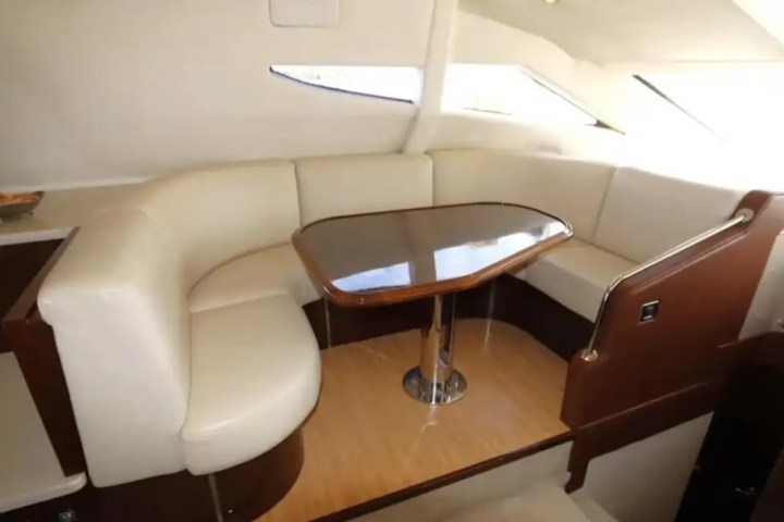 Luxurious yacht interior with curved seating and a wooden table.