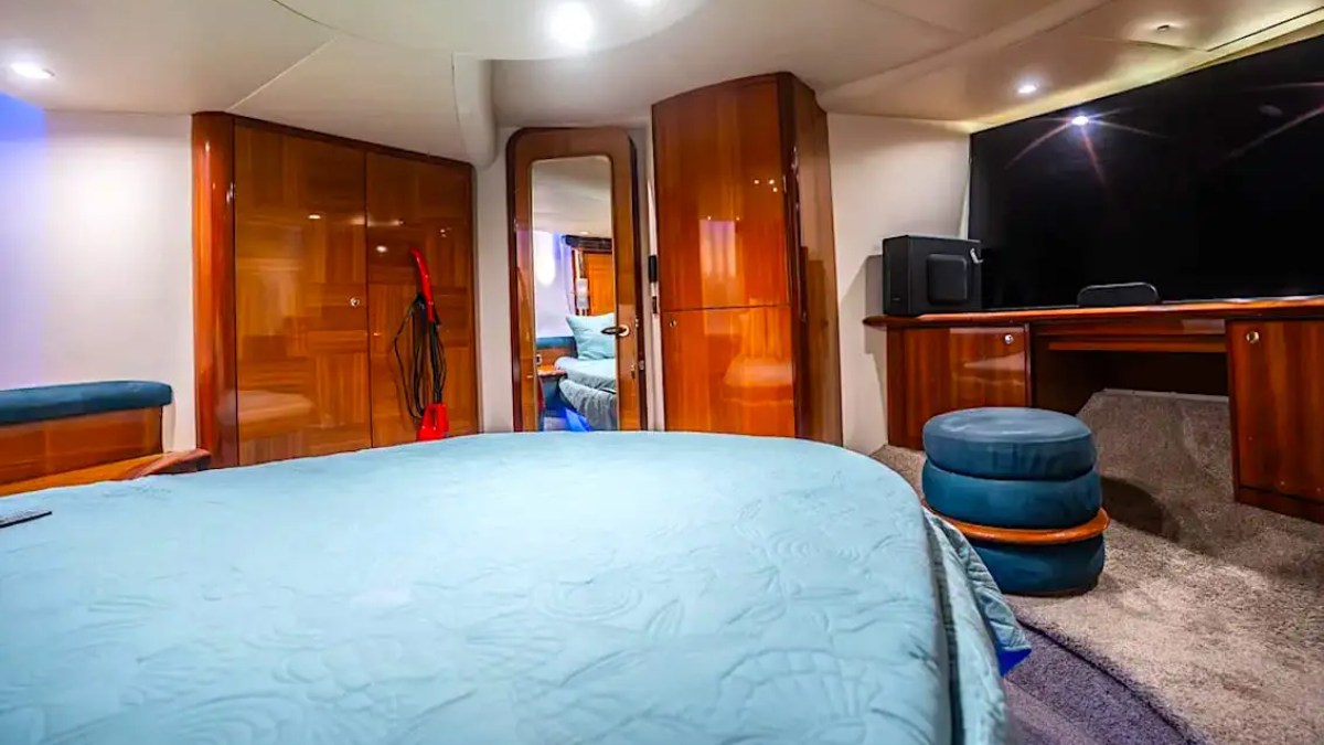 Luxurious yacht cabin with bed, seating area, and wooden cabinets.