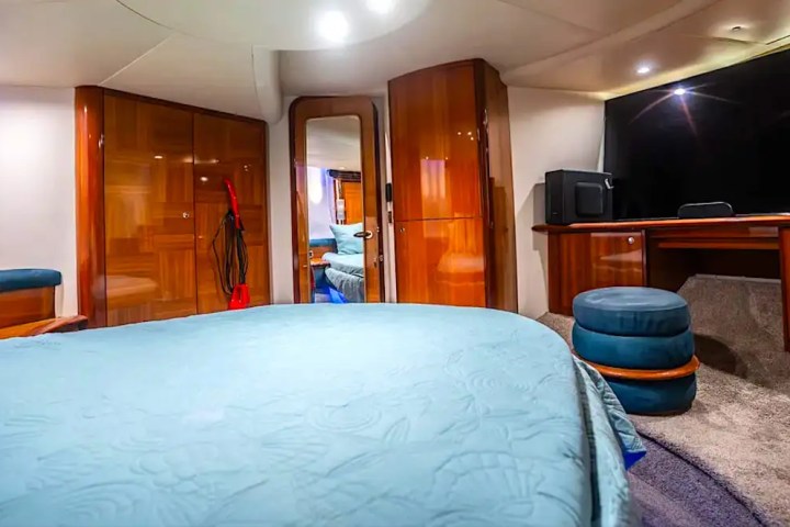 Luxurious yacht cabin with bed, seating area, and wooden cabinets.