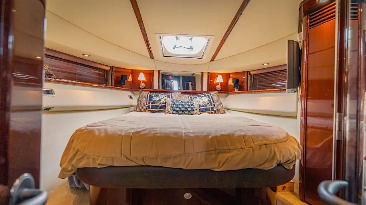 Luxurious boat cabin with a large bed, wooden panels, and ambient lighting.