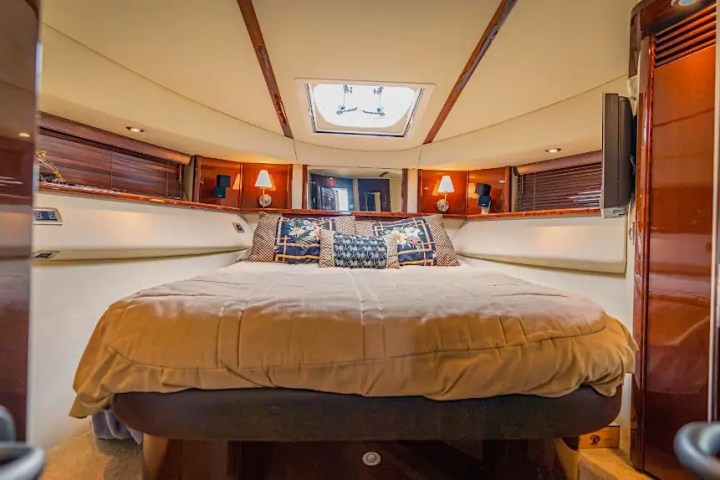 Luxurious boat cabin with a large bed, wooden panels, and ambient lighting.