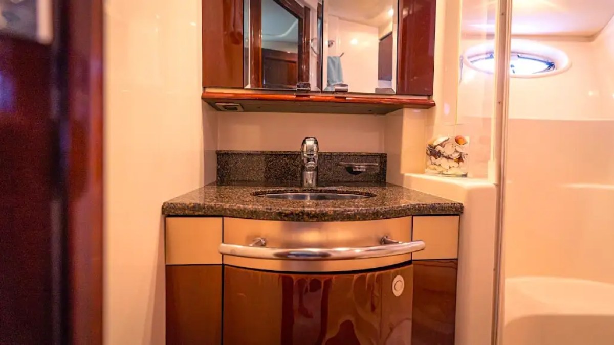 Modern yacht bathroom with wood cabinets, mirror, and a round sink with faucet.