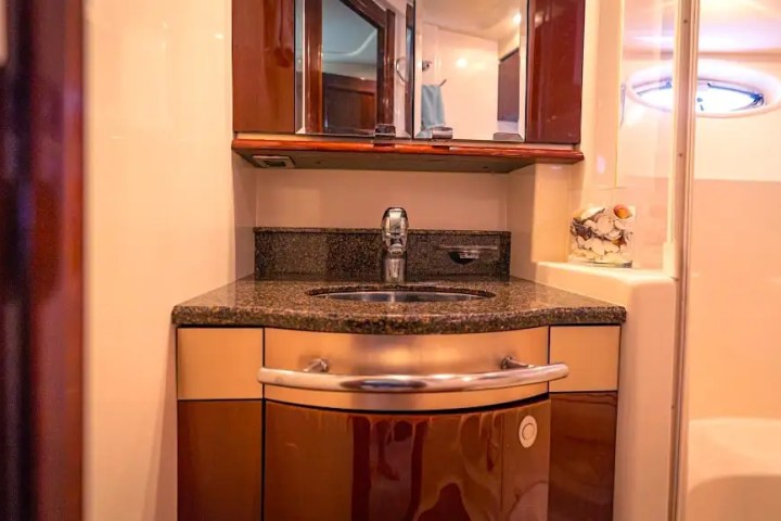 Modern yacht bathroom with wood cabinets, mirror, and a round sink with faucet.