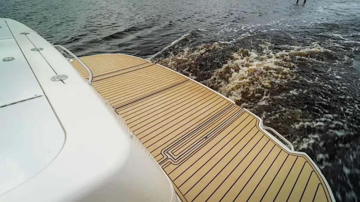 Boat deck with wooden finish, water splashing in the background.