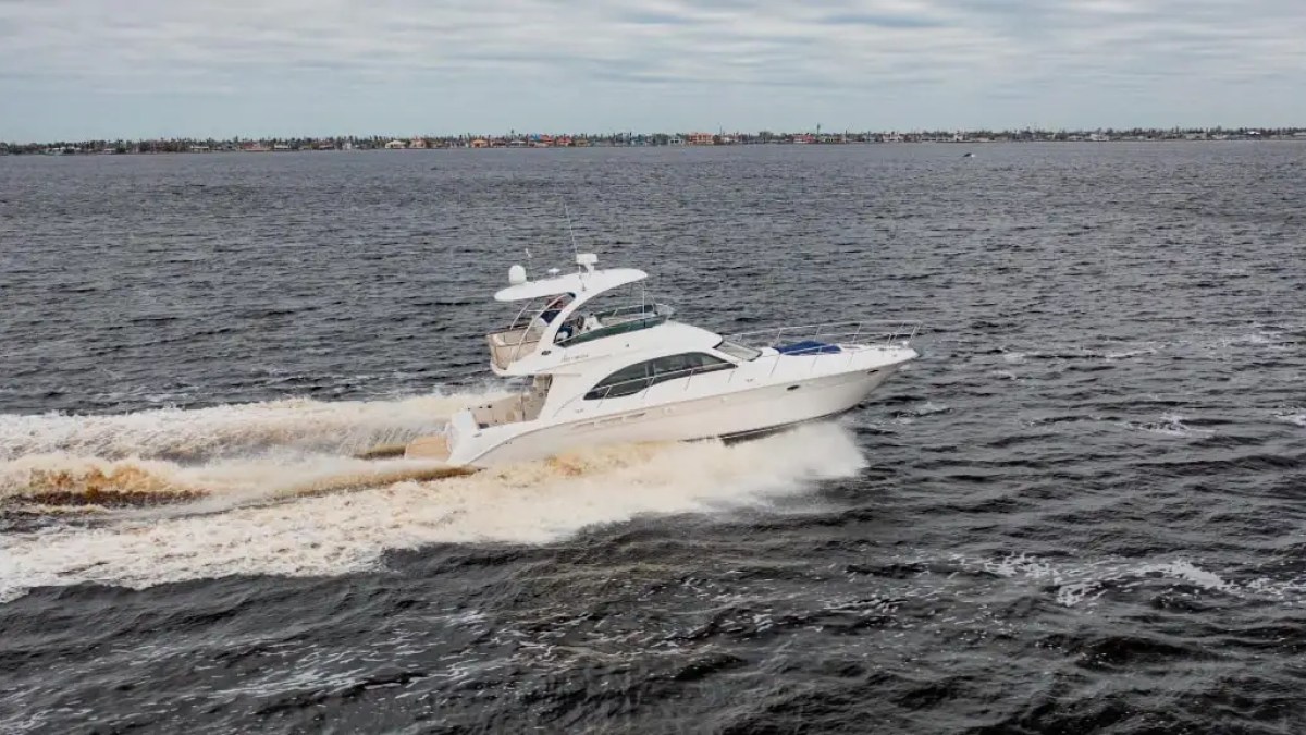 White yacht cruising on open water under a cloudy sky.