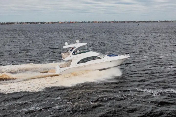White yacht cruising on open water under a cloudy sky.