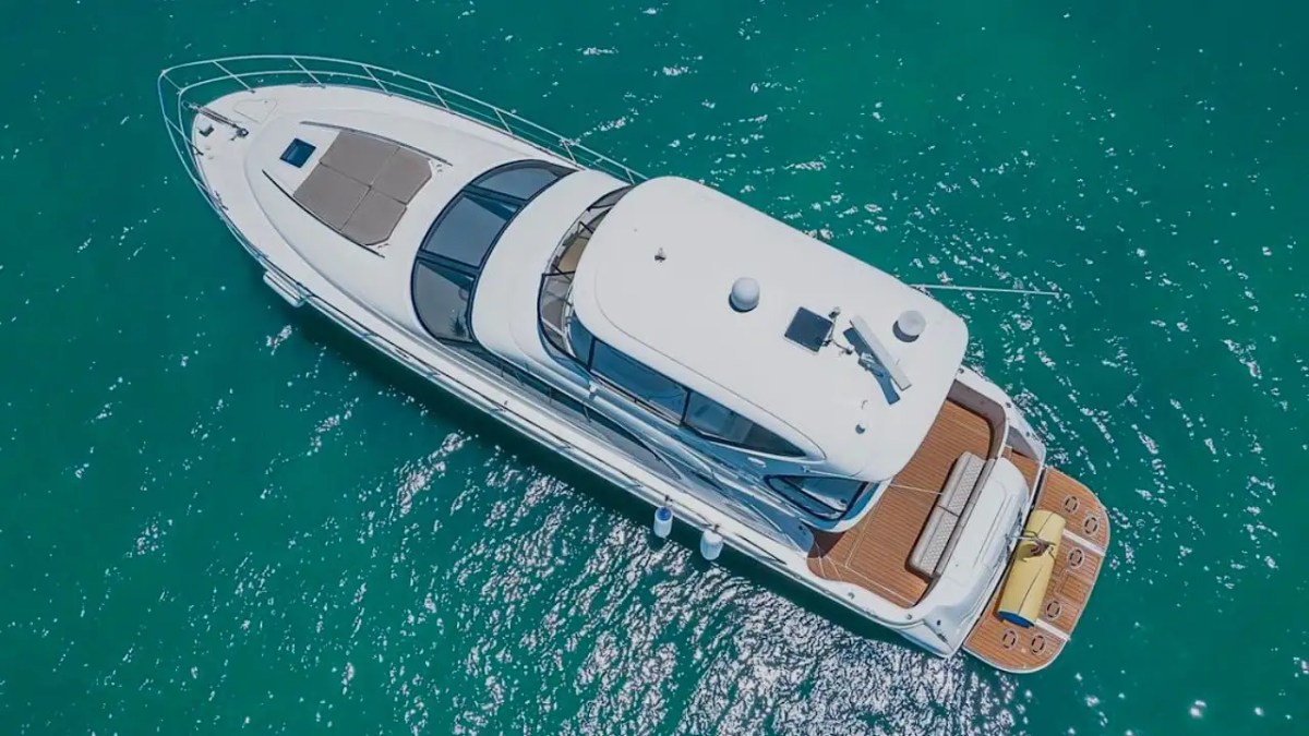 Aerial view of a luxury yacht on clear turquoise water.