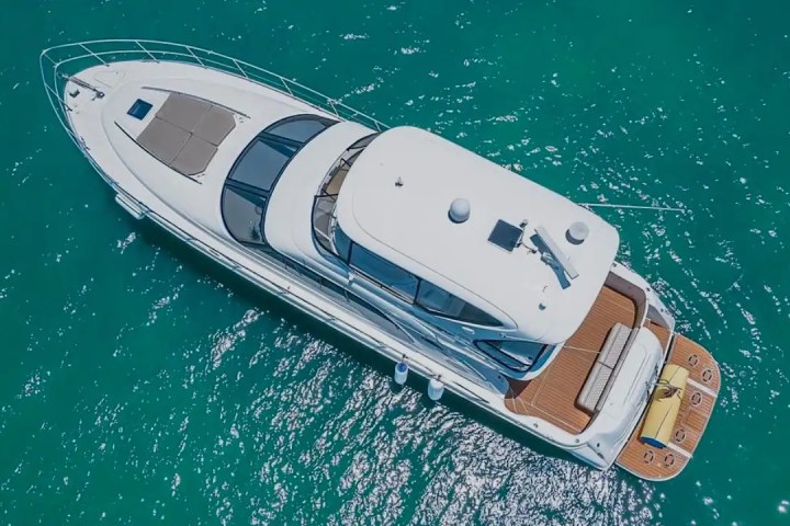 Aerial view of a luxury yacht on clear turquoise water.