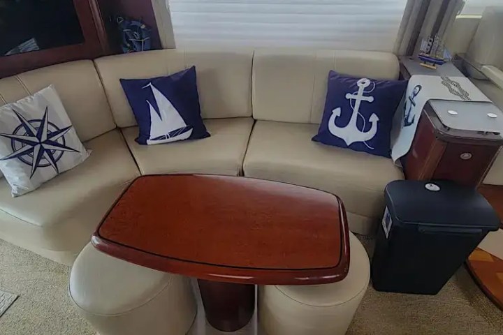Nautical-themed couch with pillows showing compass, sailboat, and anchor designs, beside a compact table and bin.