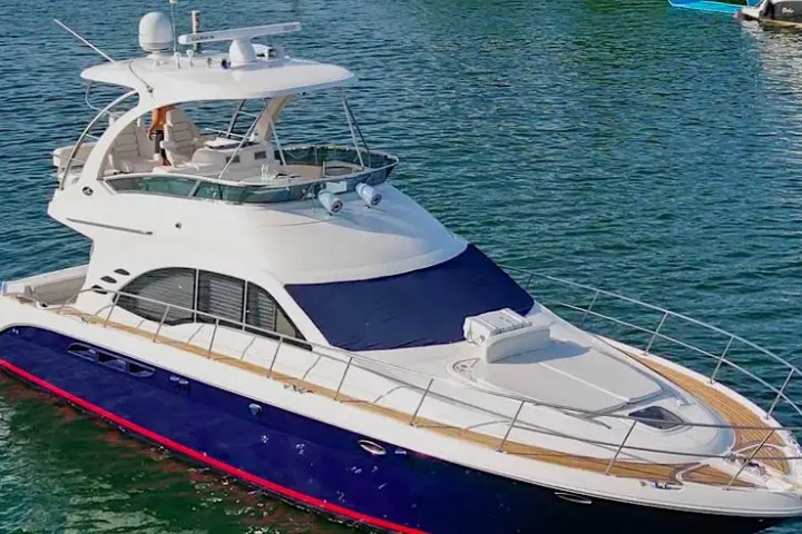 Large white and blue yacht with two decks docked on calm water.