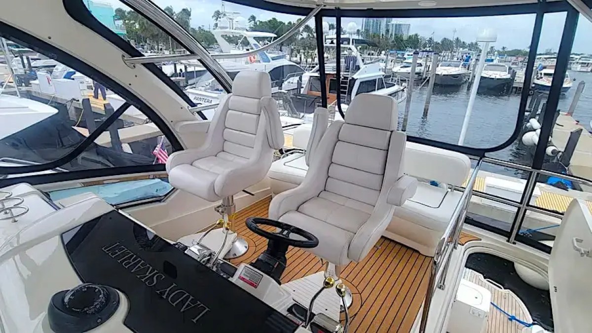 Interior of a yacht helm with two white captain chairs and view of marina.
