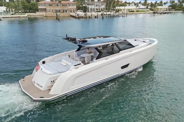 Luxury motor yacht cruising on a calm waterway near waterfront homes.