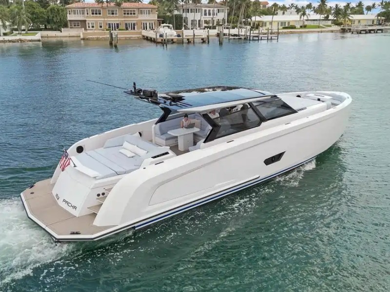 Luxury motor yacht cruising on a calm waterway near waterfront homes.
