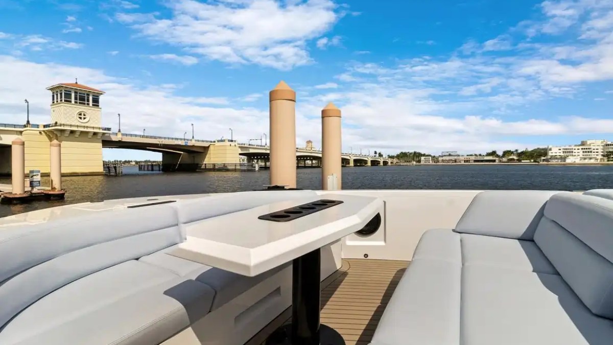 Boat deck with seating looking at bridge over water under blue sky.