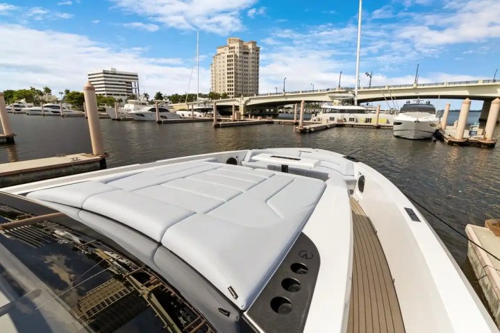 Luxury yacht docked at a marina with buildings and a bridge in the background.