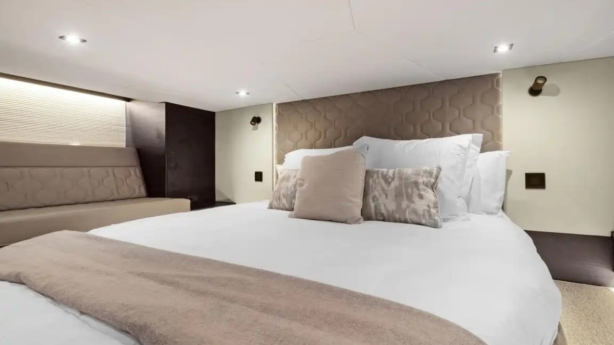 Modern bedroom with a large bed, beige headboard, and minimalistic decor.