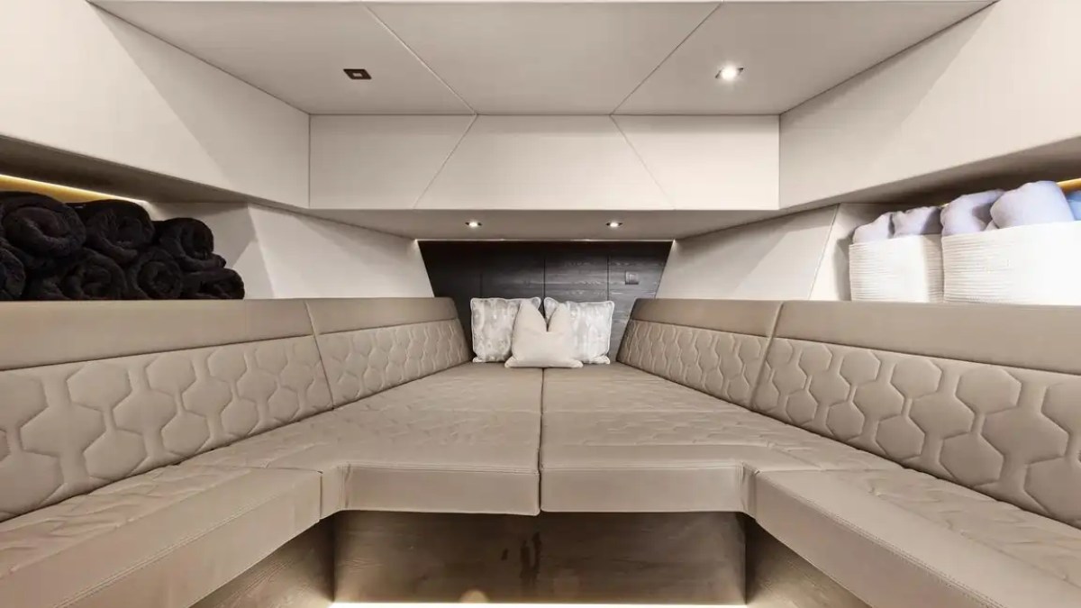 Luxurious boat cabin with beige quilted seats, cushions, and rolled towels.