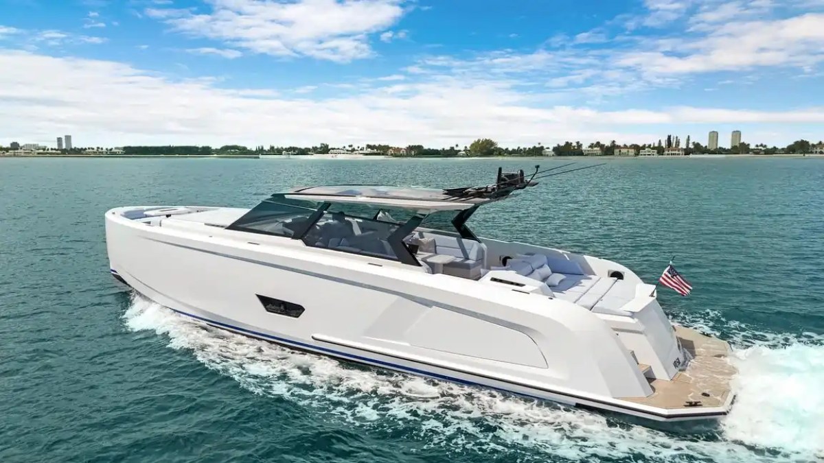 Modern white yacht cruising on blue water with a city skyline in the background.